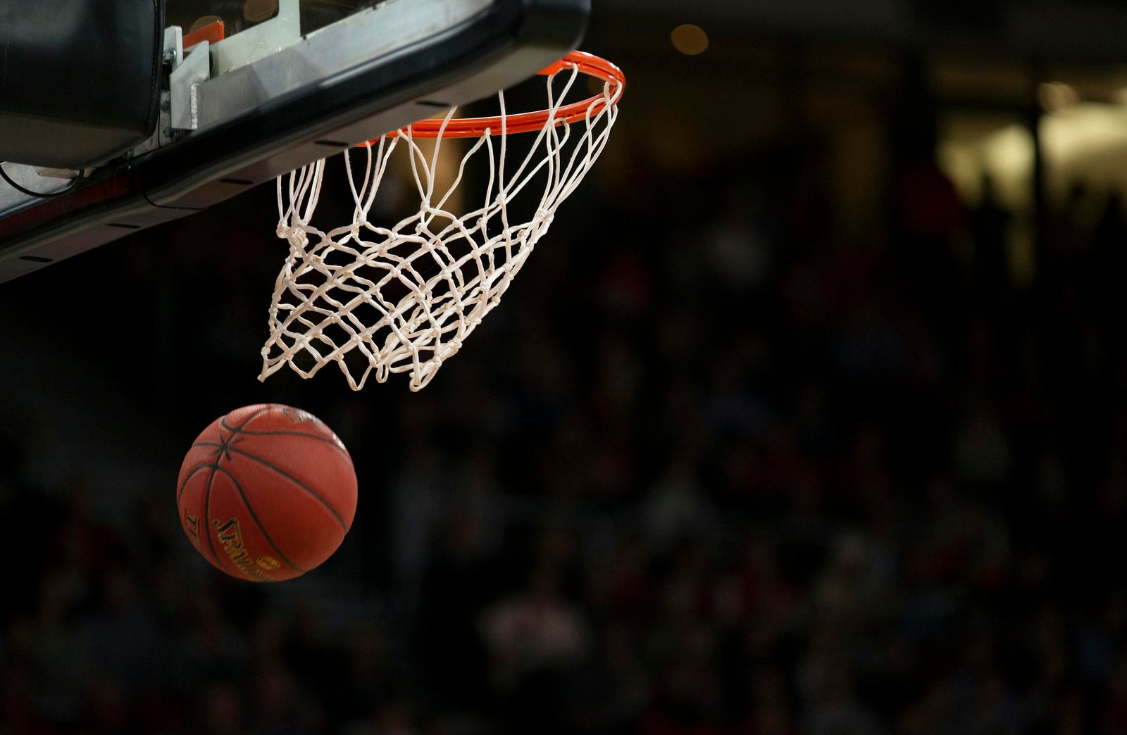 A basketball going through the hoop during a fast-paced game, capturing the excitement of the sport.