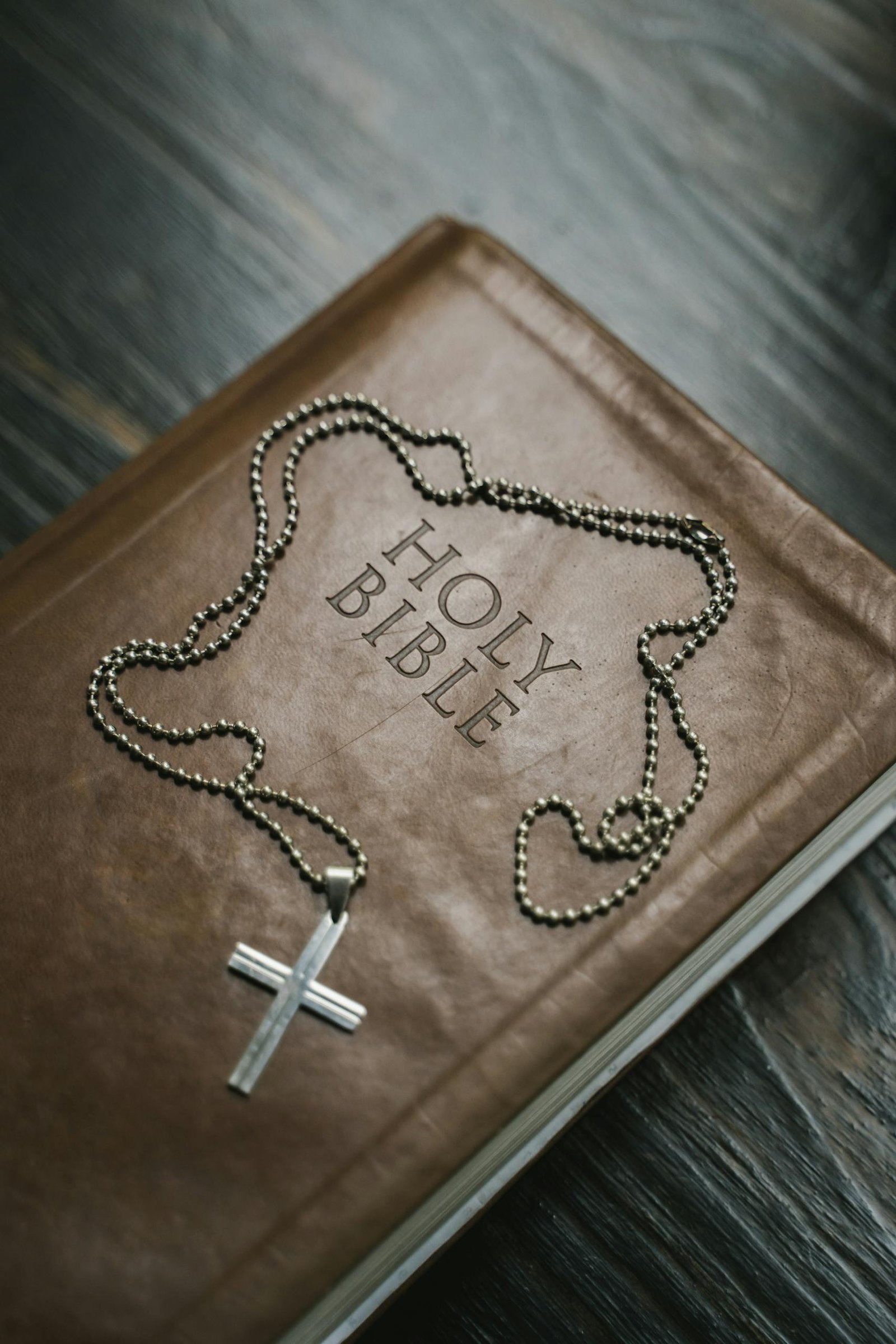 Close-up image of a Holy Bible with a cross necklace, emphasizing Christian faith.