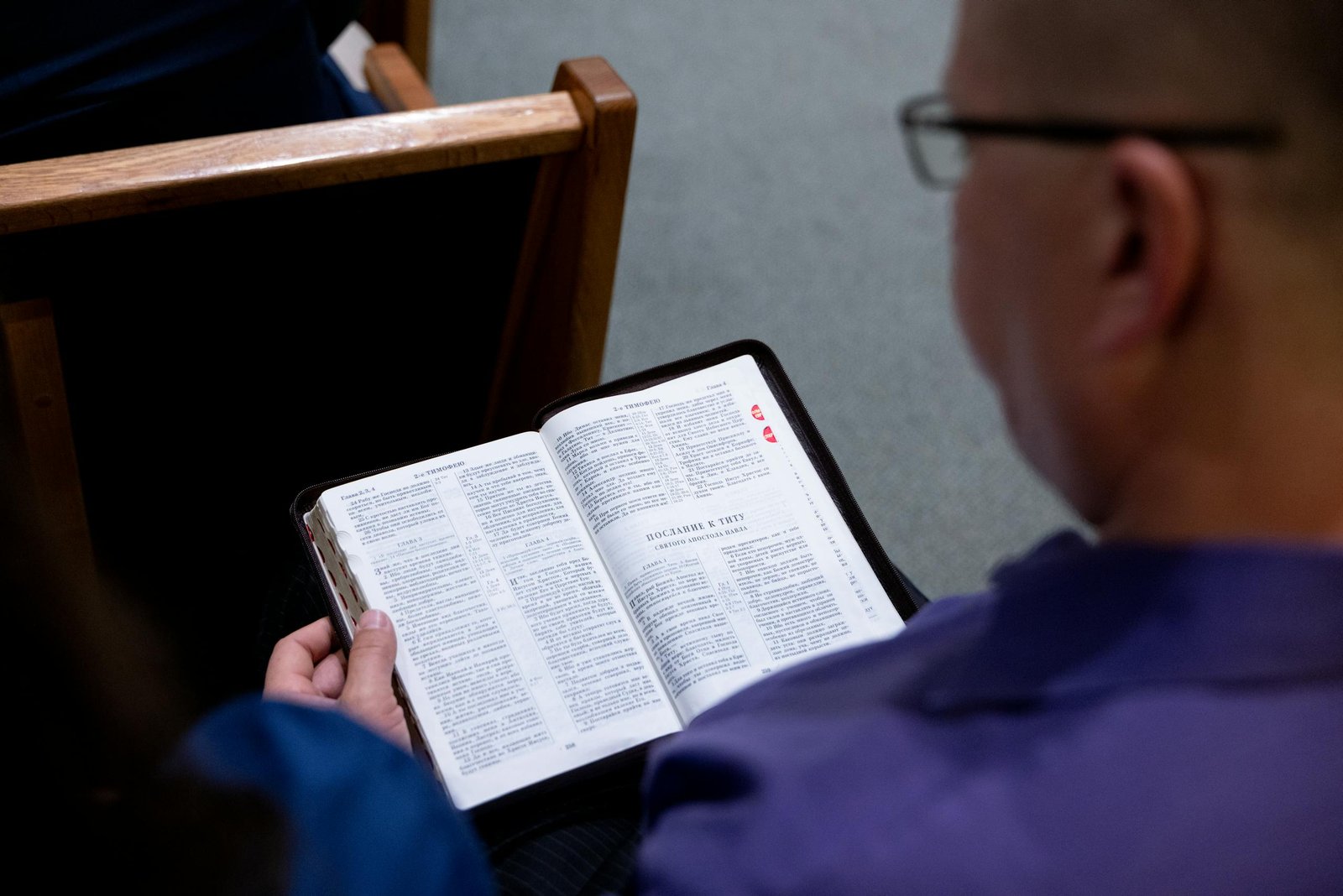 Daily Bible verse 4-18-2026 1 An individual studies a Bible while seated in a church. Focus on faith and reflection.